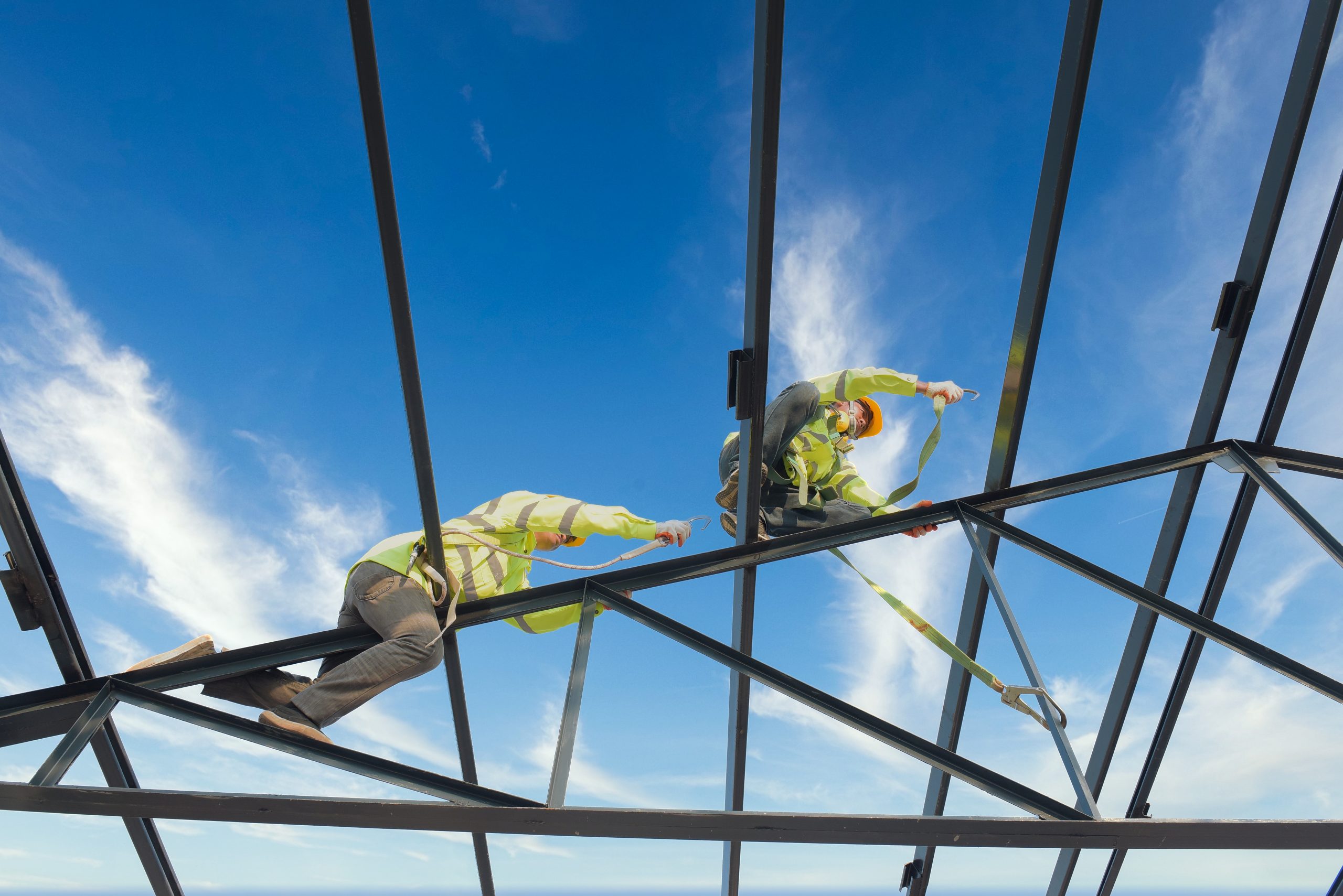 Construction workers wear safety harnesses and safety harnesses working on industrial metal roofs.